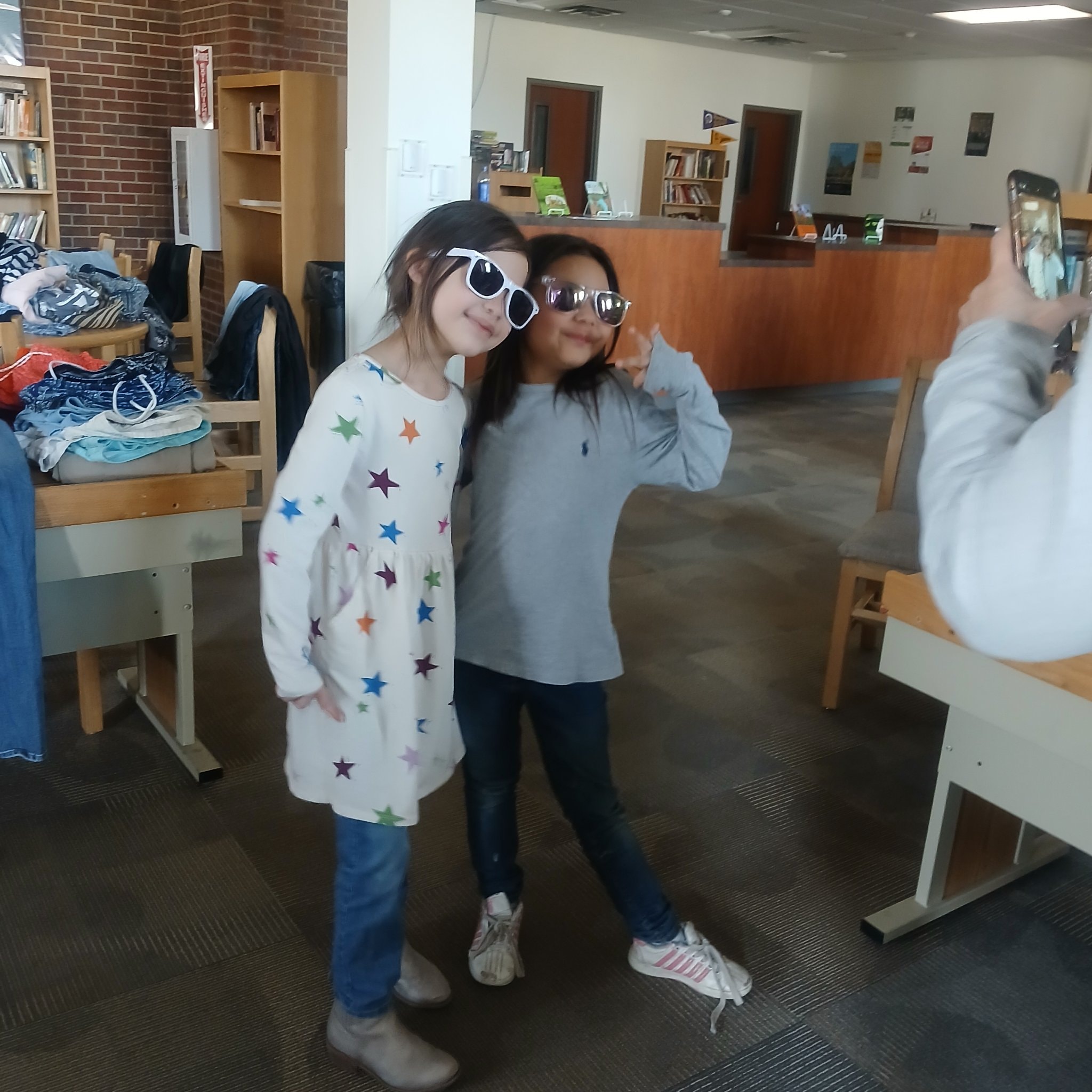 Two girls wearing oversized sunglasses at community event