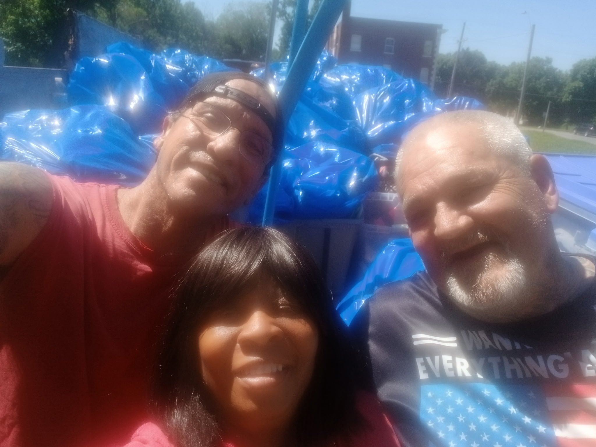 Three community members with blue supply bags