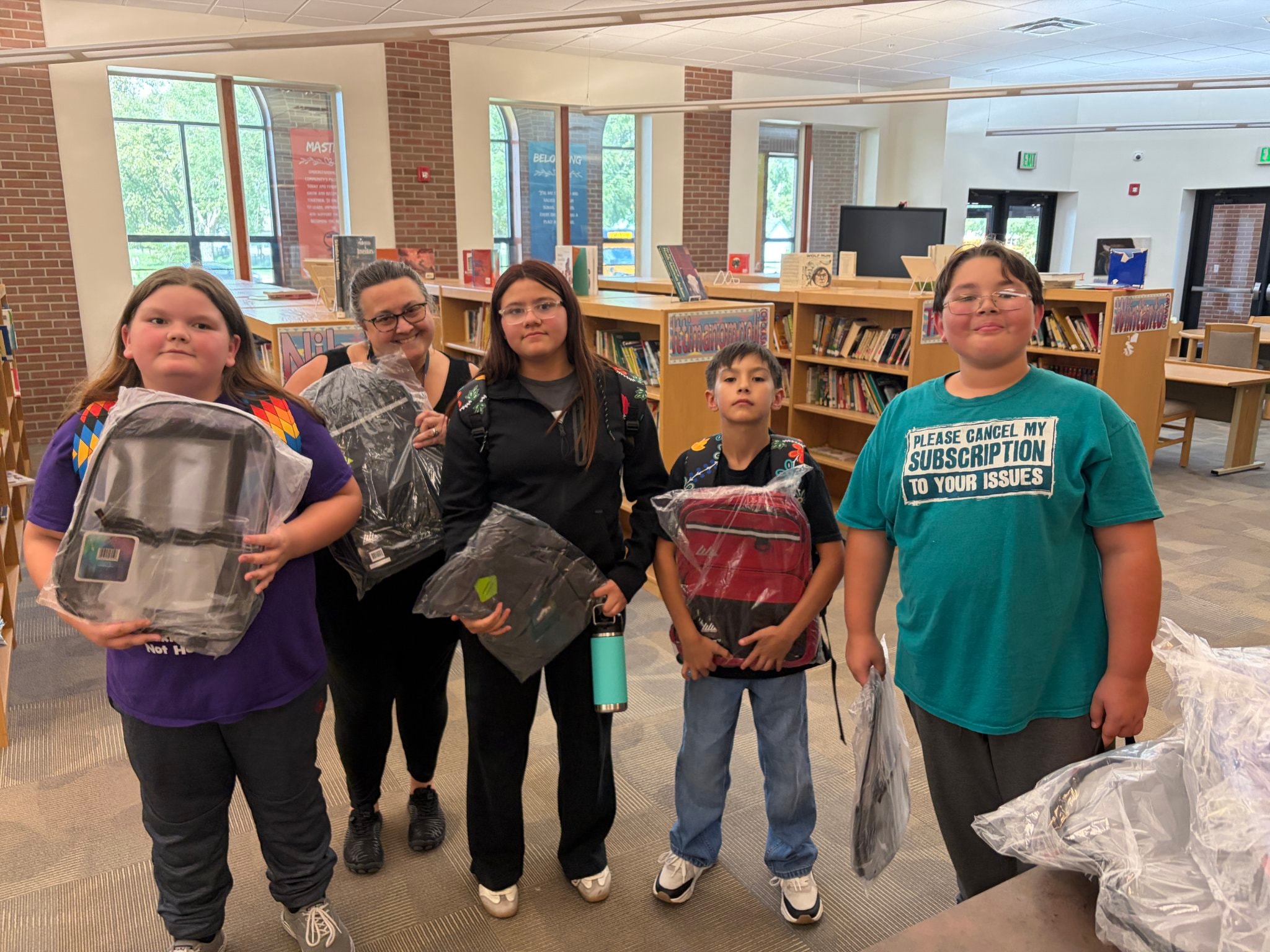 Children holding backpacks in the library