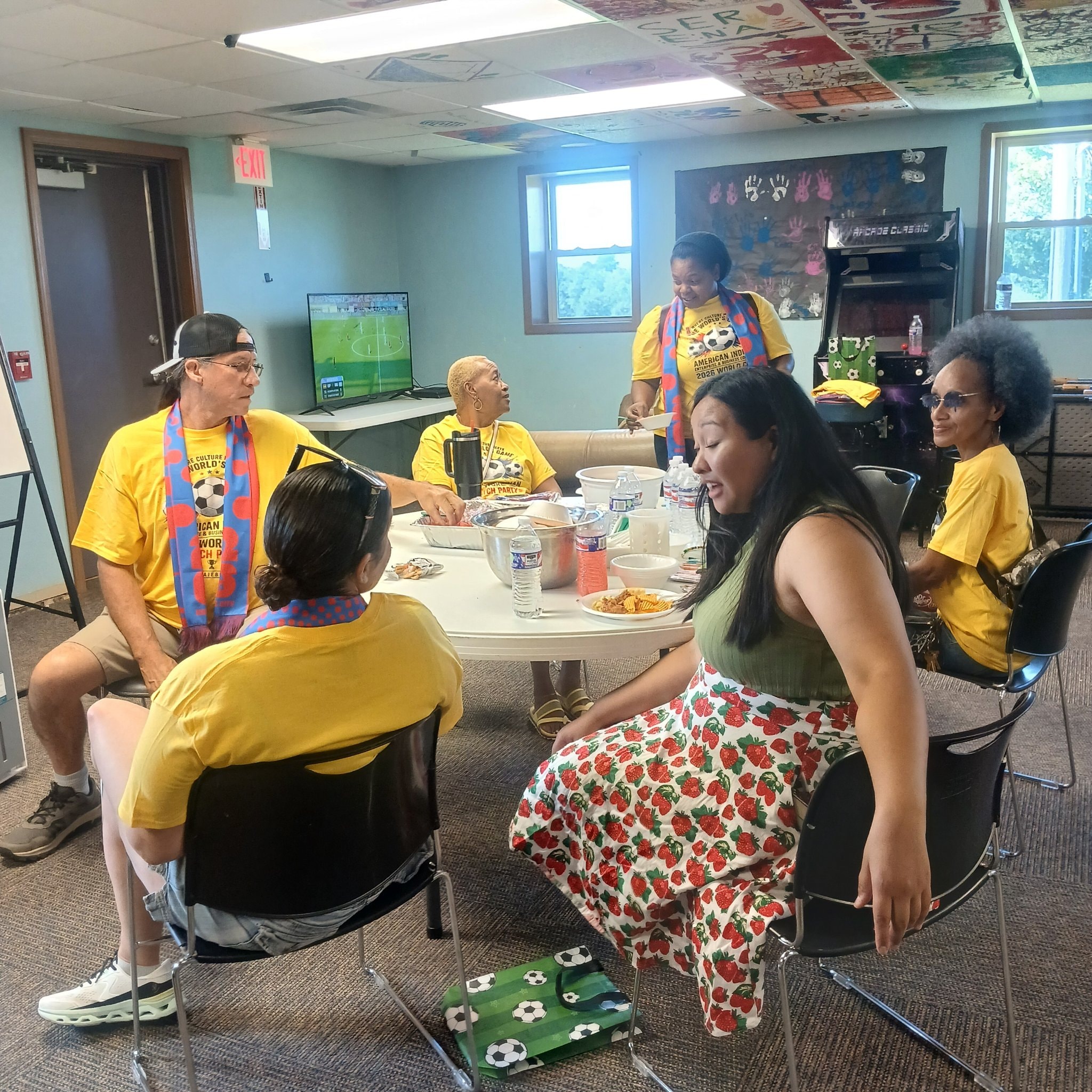 World Cup watch party group around a food table in yellow shirts